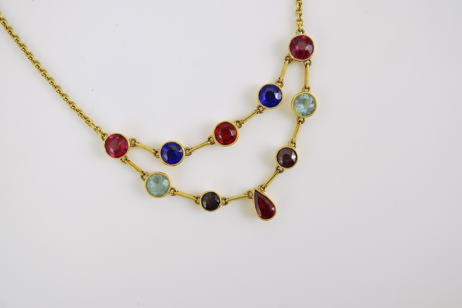 An early 20th century 15ct gold and ten stone multi coloured doublet set necklace